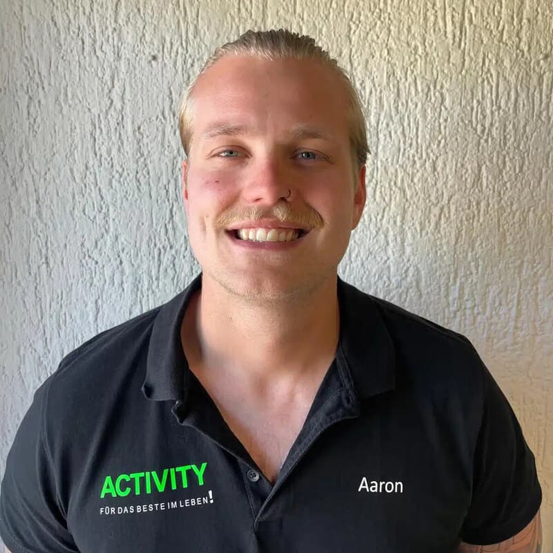 Aaron, Trainer in Bürstadt, im schwarzen ACTIVITY-Shirt vor heller Wand